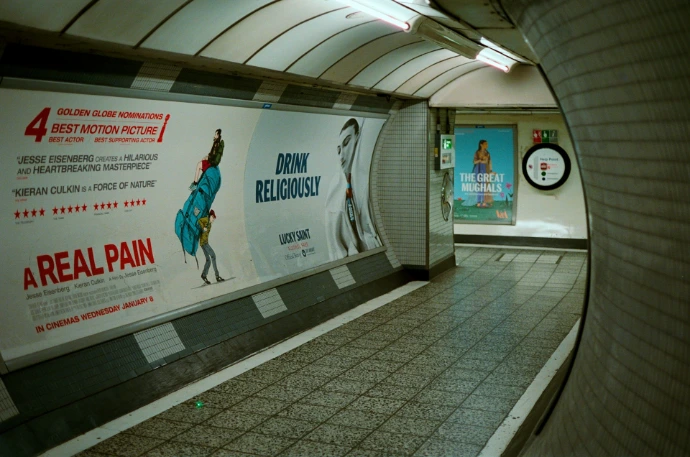 Subway tunnel with advertisements and tiled walls.